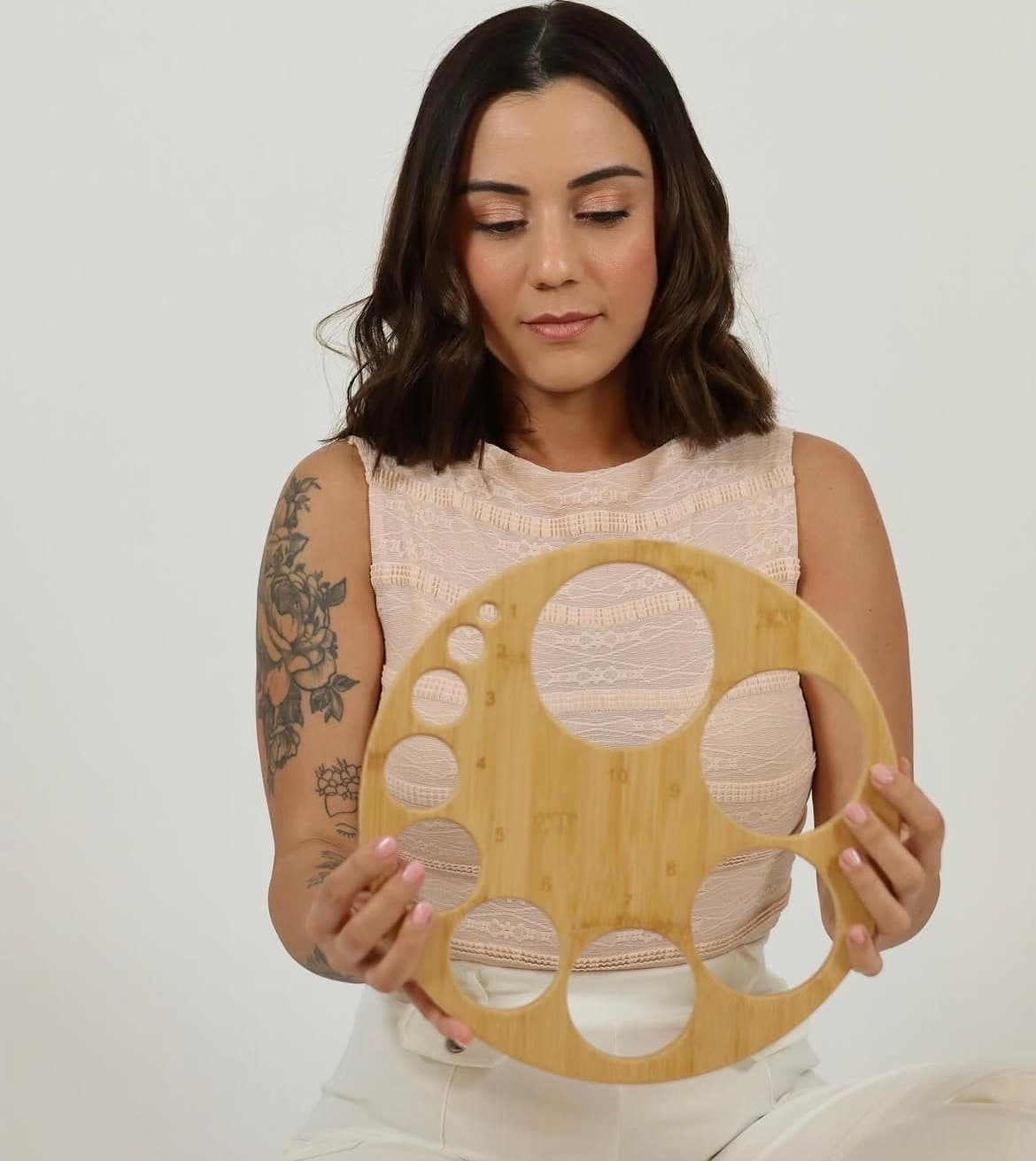 Woman holding a circular wooden breastfeeding measurement tool